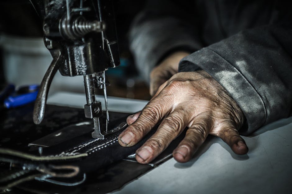 Detailed capture of hands working with a sewing machine, showcasing craftsmanship and textile work.