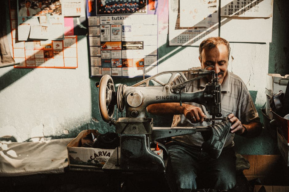 Cobbler working on shoe repair in a vintage workshop with an antique sewing machine.