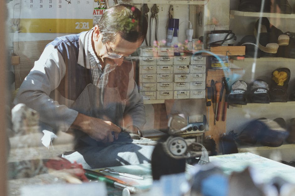 An experienced shoemaker working in a traditional workshop, surrounded by tools and materials.